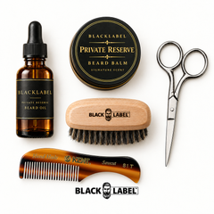 A curated beard grooming set arranged on a white background, including an amber glass dropper bottle of Blacklabel Beard Oil, a round tin of Blacklabel Private Reserve Beard Balm, a wooden beard brush, silver scissors, and a tortoiseshell comb. A Blacklabel logo appears below the tools.